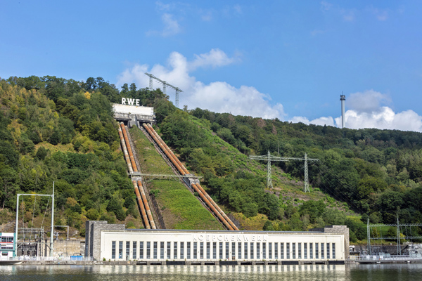 DEU, Deutschland, Koepchenwerk, Herdecke, Pumpspeicherwerk, Industrielles Erbe 29.07.2019 Das Koepchenwerk ist ein national bedeutsames Monument der Energiewirtschaft. Es wurde in den Jahren 1927 bis 1930 errichtet. Seinen Namen trägt es nach seinem Ideengeber und damaligen RWE-Vorstand, Prof. Dr. Arthur Koepchen. Das Koepchenwerk ist eines der beiden ersten Pumpspeicherkraftwerke Deutschlands und im nahezu authentischen technischen wie baulichen Zustand erhalten. Dazu zählen unter anderem die historische Maschinenhalle mit Kommandohaus inklusive der vier originalen Maschinensätze. Sie bestehen jeweils aus Turbine, Motor-Generator, Kupplung und Pumpe. Außerdem gehören dazu die vier markanten Druckrohrleitungen sowie das Schieberhaus mit dem Firmenschriftzug.Die Entwicklung der Pumpspeichertechnik in den 1920er Jahren war eine große Pionierleistung, die den fortschrittlichen Ausbau eines europäischen Verbundnetzes ermöglichte. Nach einem im Dezember 1980 aufgetretenen Schaden und nach ersten Reparaturmaßnahmen war das Koepchenwerk nur bedingt wieder einsatzfähig. 1981 entschied der RWE-Vorstand, dass unmittelbar neben dem Koepchenwerk ein neues und hochmodernes Pumpspeicherkraftwerk entstehen sollte. Dieses wurde zwischen 1985-1989 errichtet und 1989 als Pumpspeicherkraft Herdecke mit 153 Megawatt Leistung in Betrieb genommen. 1994 wurde das Koepchenwerk stillgelegt. Die Voreigentümerin, die RWE Power AG, hat das hochrangige Denkmal im Jahr 2017 in das Eigentum der Stiftung Industriedenkmalpflege und Geschichtskultur übertragen, wodurch es vor dem Abbruch bewahrt werden konnte. [ (c) Markus Bollen / P h o t o - D e s i g n, J o h a n n - B e n d e l - S t r. 16a, 51429 B e r g i s c h  G l a d b a c h, fon: 02204 22220, m.bollen@t-online.de ; Kto: IBAN: DE16 6609 0800 0009 1474 38, BIC: GENODE61BBB ; Ust-ID: DE 121 984 724 ; Jegliche Nutzung des Fotos nur gegen Honorar zzgl. der gesetzlichen MwSt., vollstaendiger Namensnennung nach Paragraph 13 UrhG und 